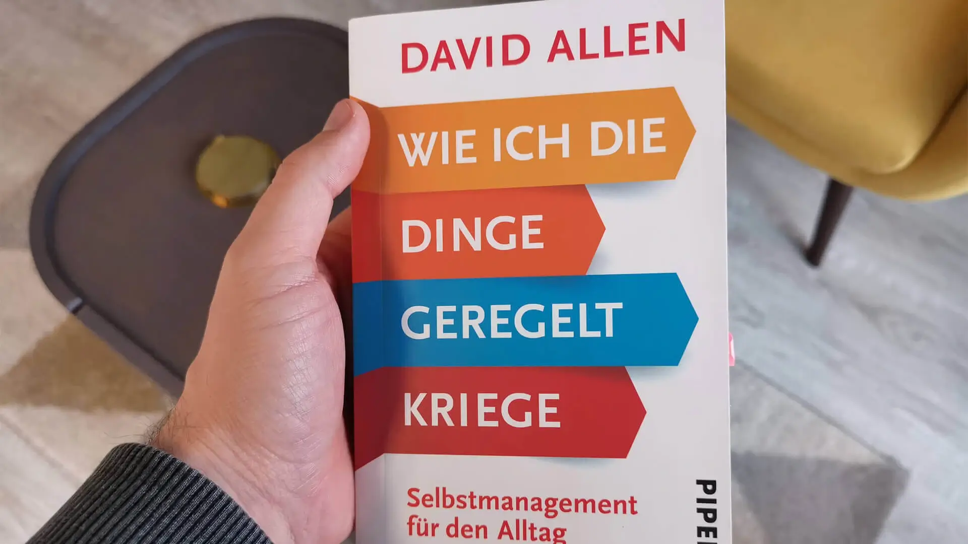 Hand hält Buch Wie ich die Dinge geregelt kriege von David Allen